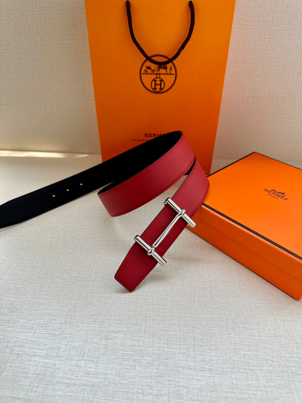 Red leather belt with silver-toned buckle and black strap laid alongside.