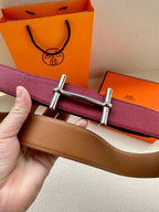 Reversible leather belt showing burgundy and tan sides with silver double-prong buckle