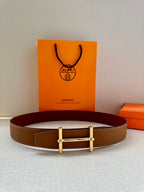 Hermes leather belt with brown strap and silver H buckle, laid flat