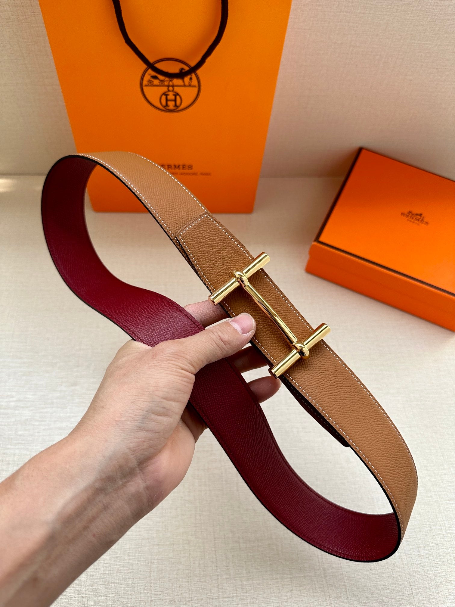 Leather belt with burgundy strap and tan keeper, gold double-prong buckle