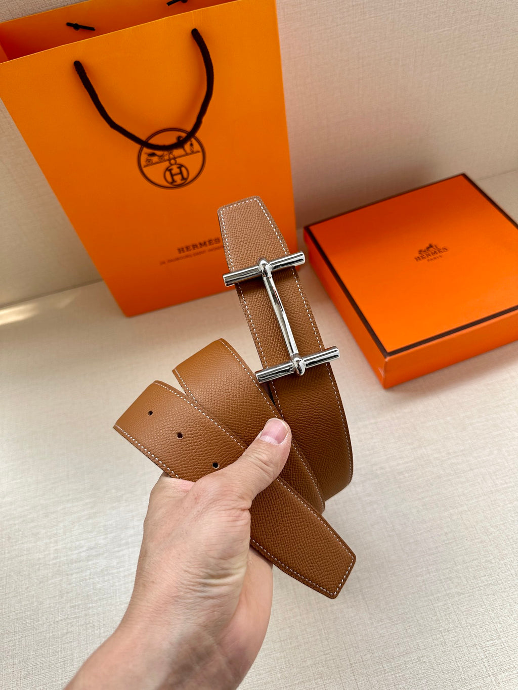 Tan leather belt with silver double-prong buckle and punched adjustment holes