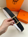 Hermes belt in dark leather, silver-tone rectangular buckle, held in hand.