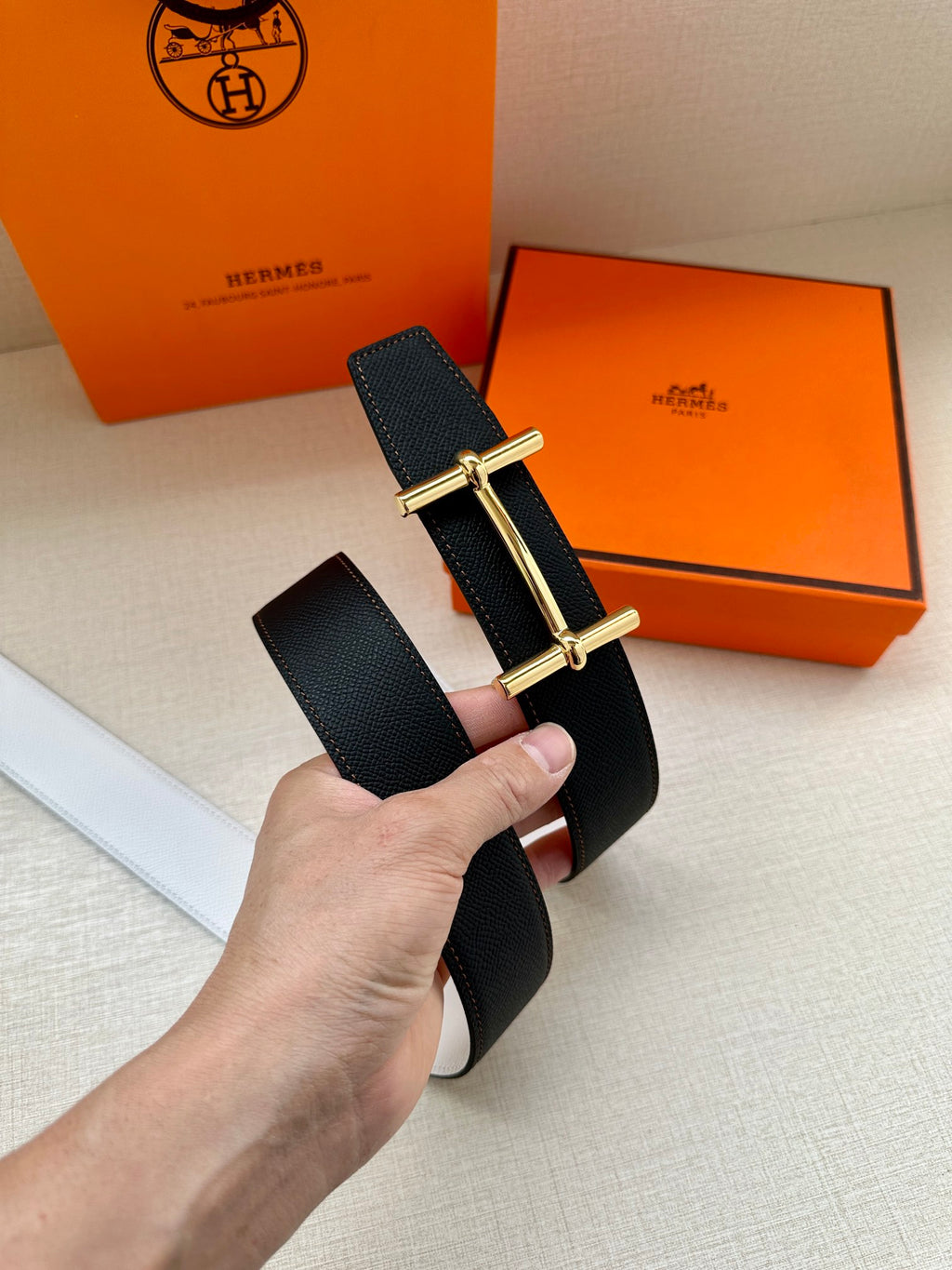 Dark leather belt with silver-tone buckle, shown with orange storage boxes.