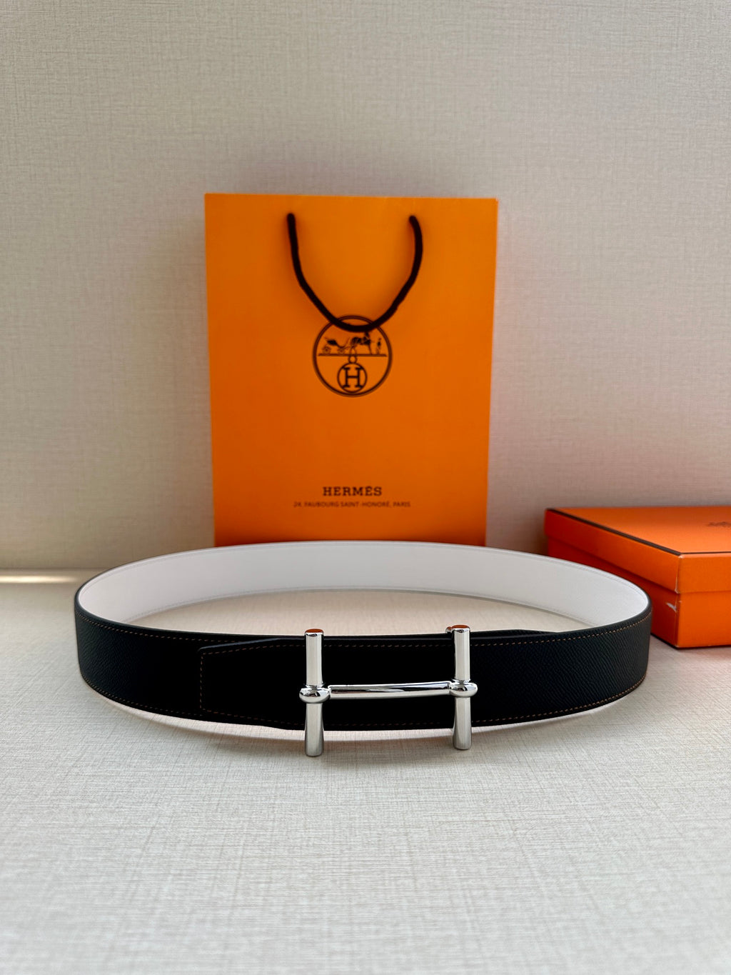 Two-tone belt flat lay: dark leather with light lining and silver-tone buckle.