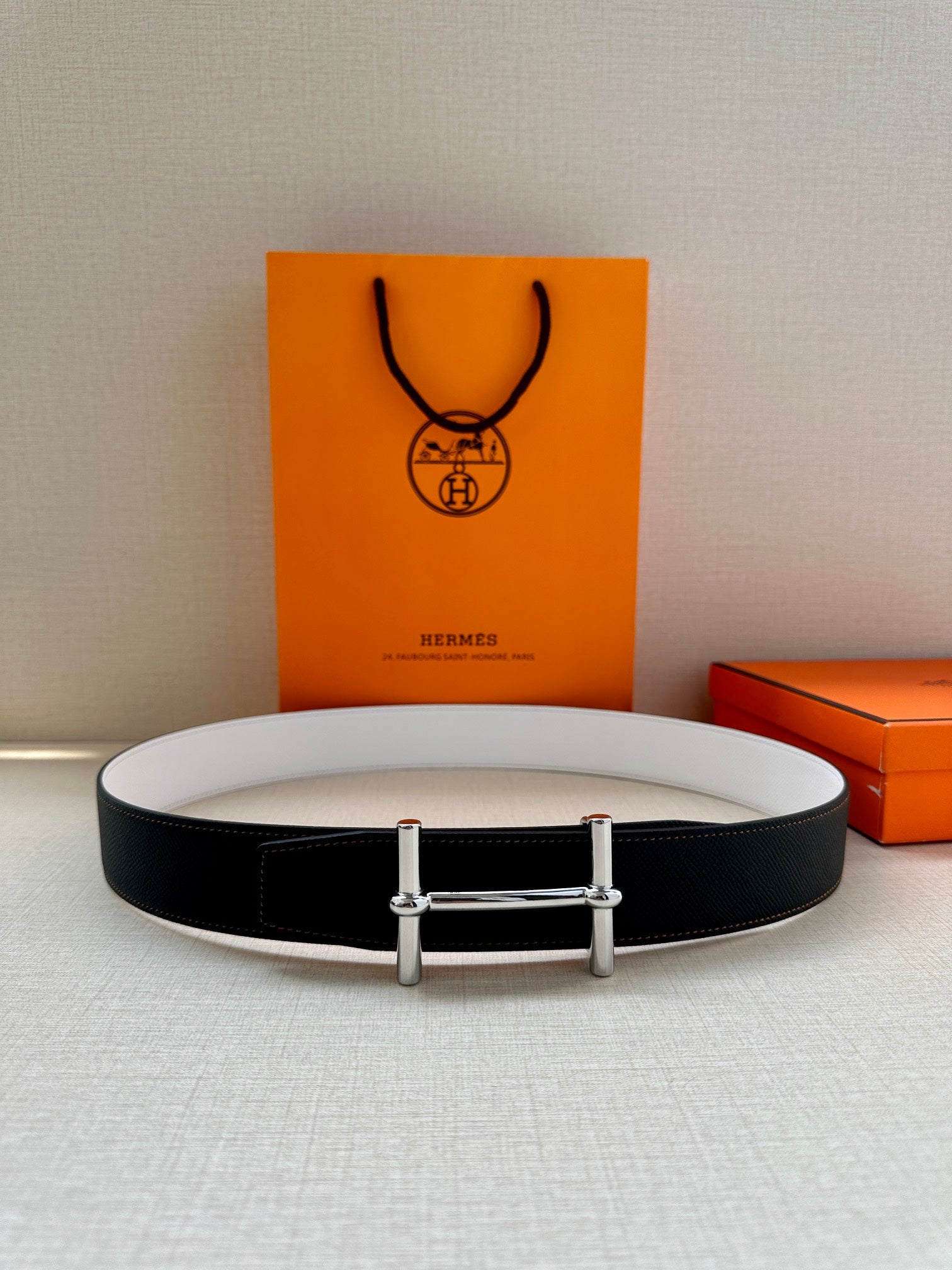 Two-tone belt flat lay: dark leather with light lining and silver-tone buckle.