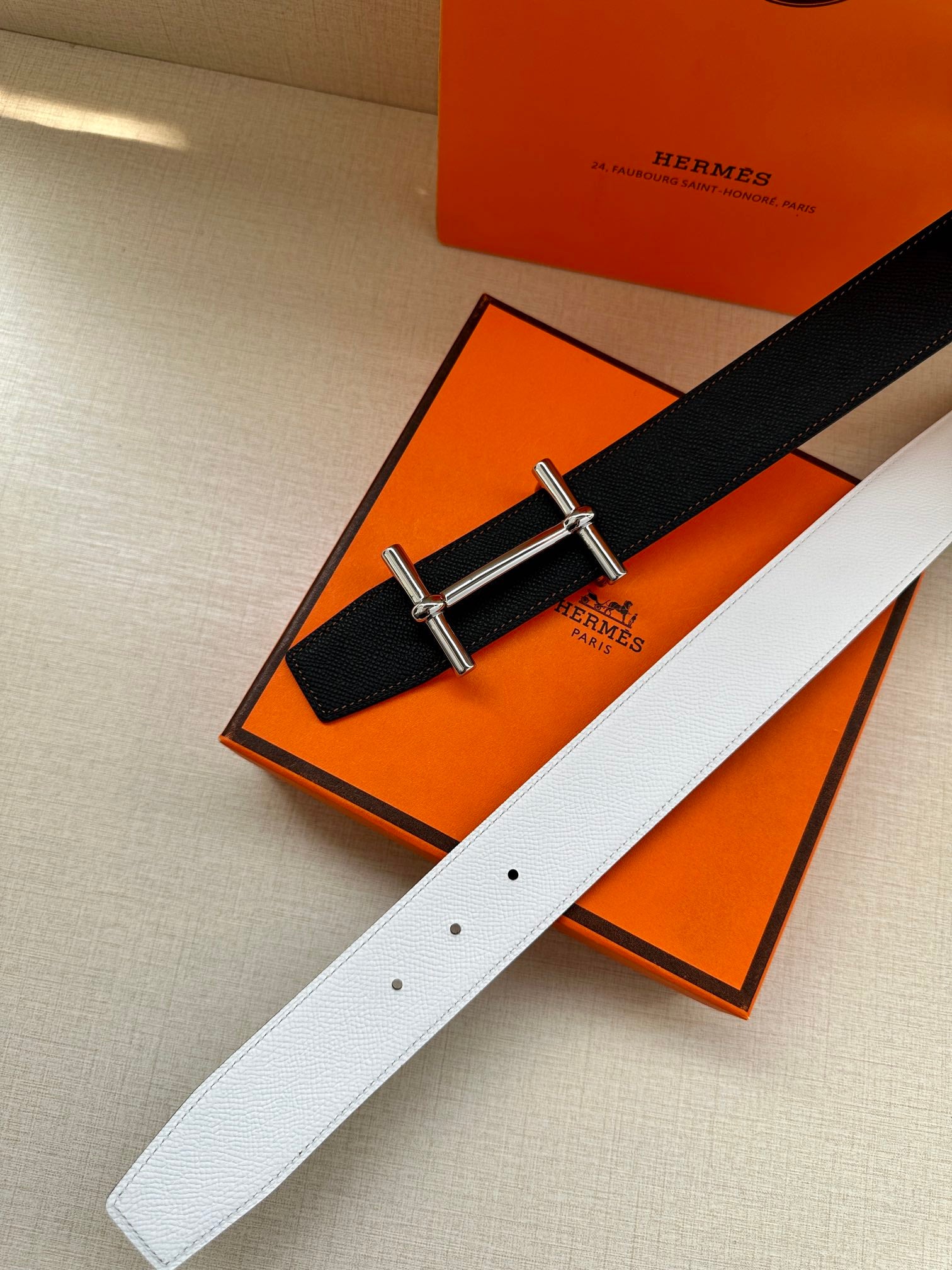 Dark leather belt with silver-tone buckle, paired with light white leather strap.