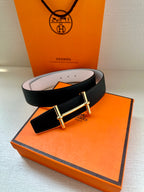Dark leather belt with silver-tone buckle, resting on orange box with light underside.