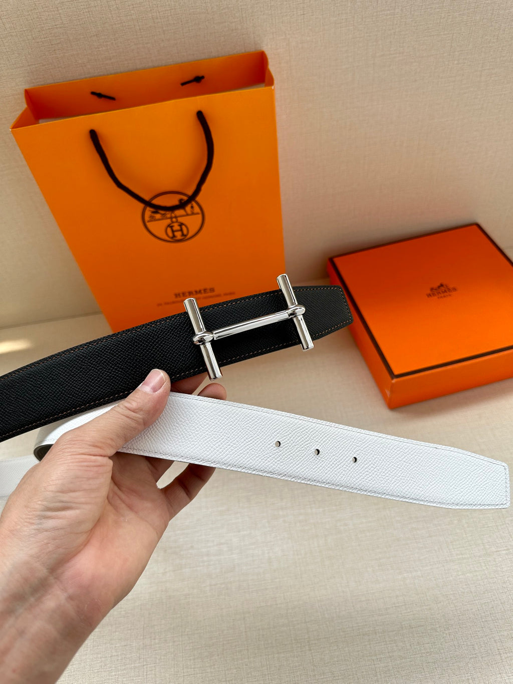 Two-tone leather belt with silver-tone buckle: dark strap and light strap, held up.