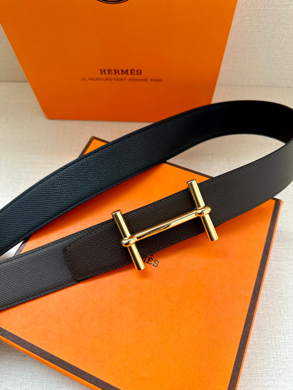 Dark leather belt with gold-tone bar buckle on textured strap