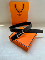 Hermes belt dark leather with silver rectangular buckle, laid on box.