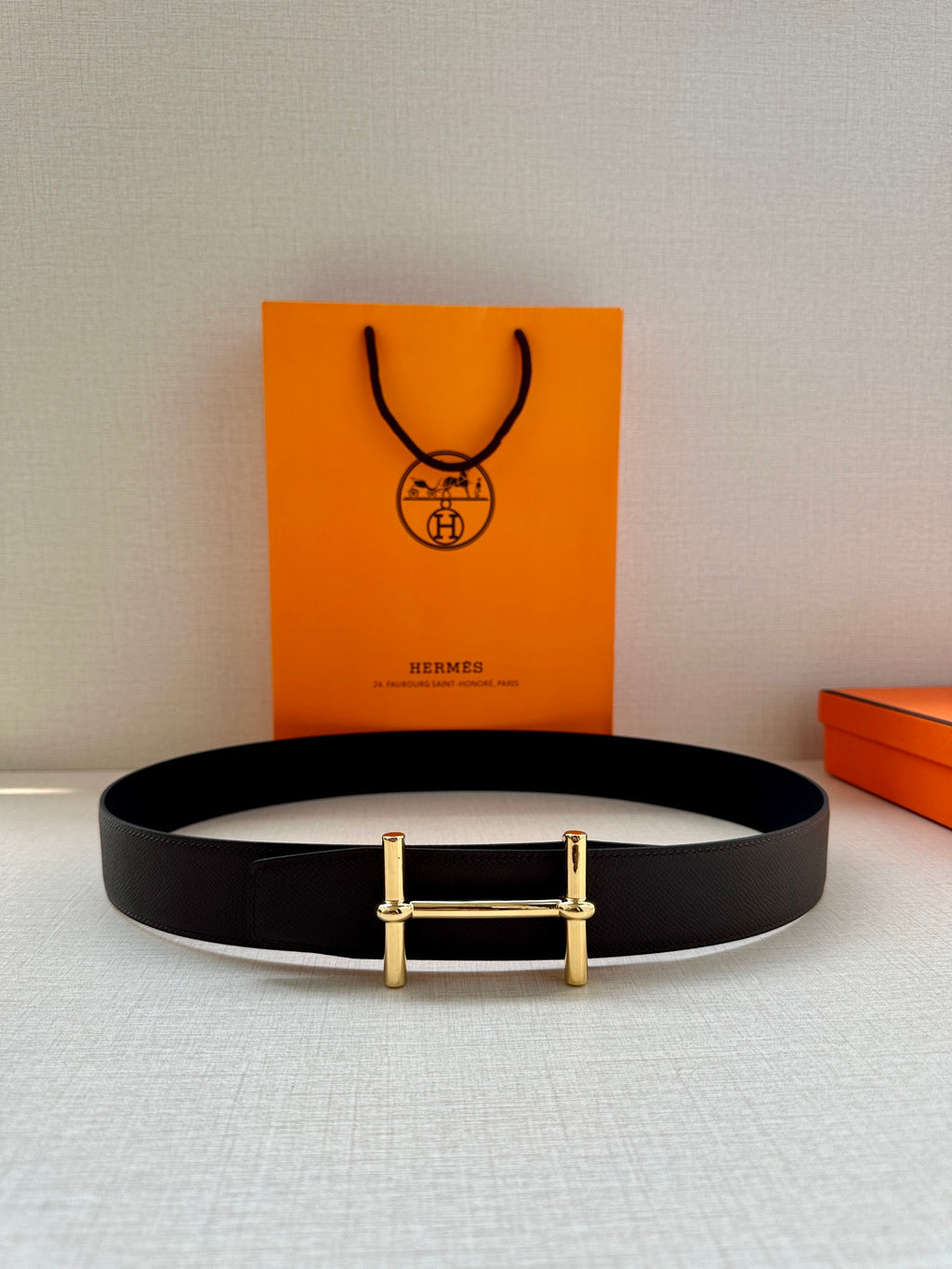 Dark leather belt with gold-tone rectangular buckle, laid flat