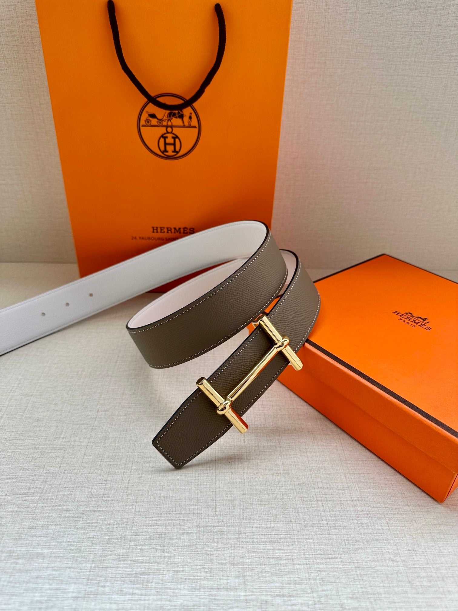 Taupe leather belt with gold double-prong buckle and white reverse strap