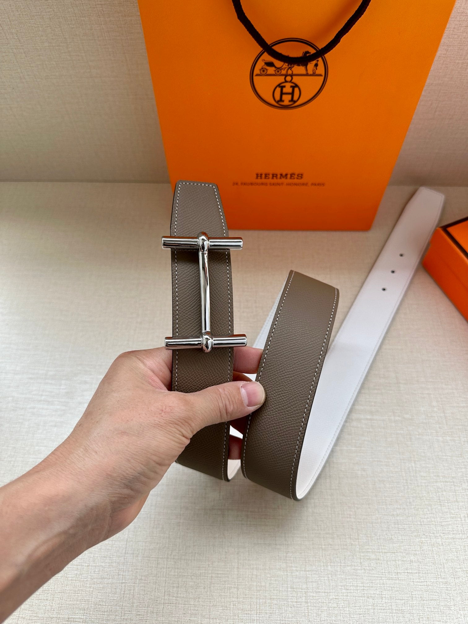 Taupe leather belt with silver-tone double-prong buckle and white reverse strap