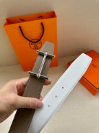 Taupe leather belt with silver double-prong buckle and white strap tip with studs