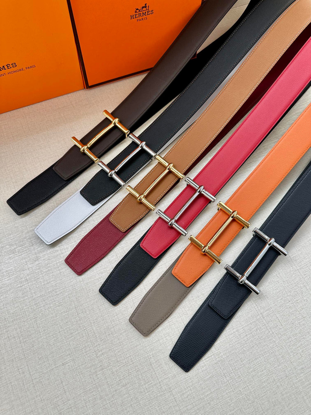Assorted leather belts with metal buckles in black, brown, white, red, and orange