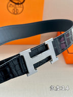Hermes belt buckle close-up with silver H clasp on dark embossed strap.