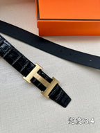 Hermes belt top view of dark leather strap with silver H buckle and perforations.