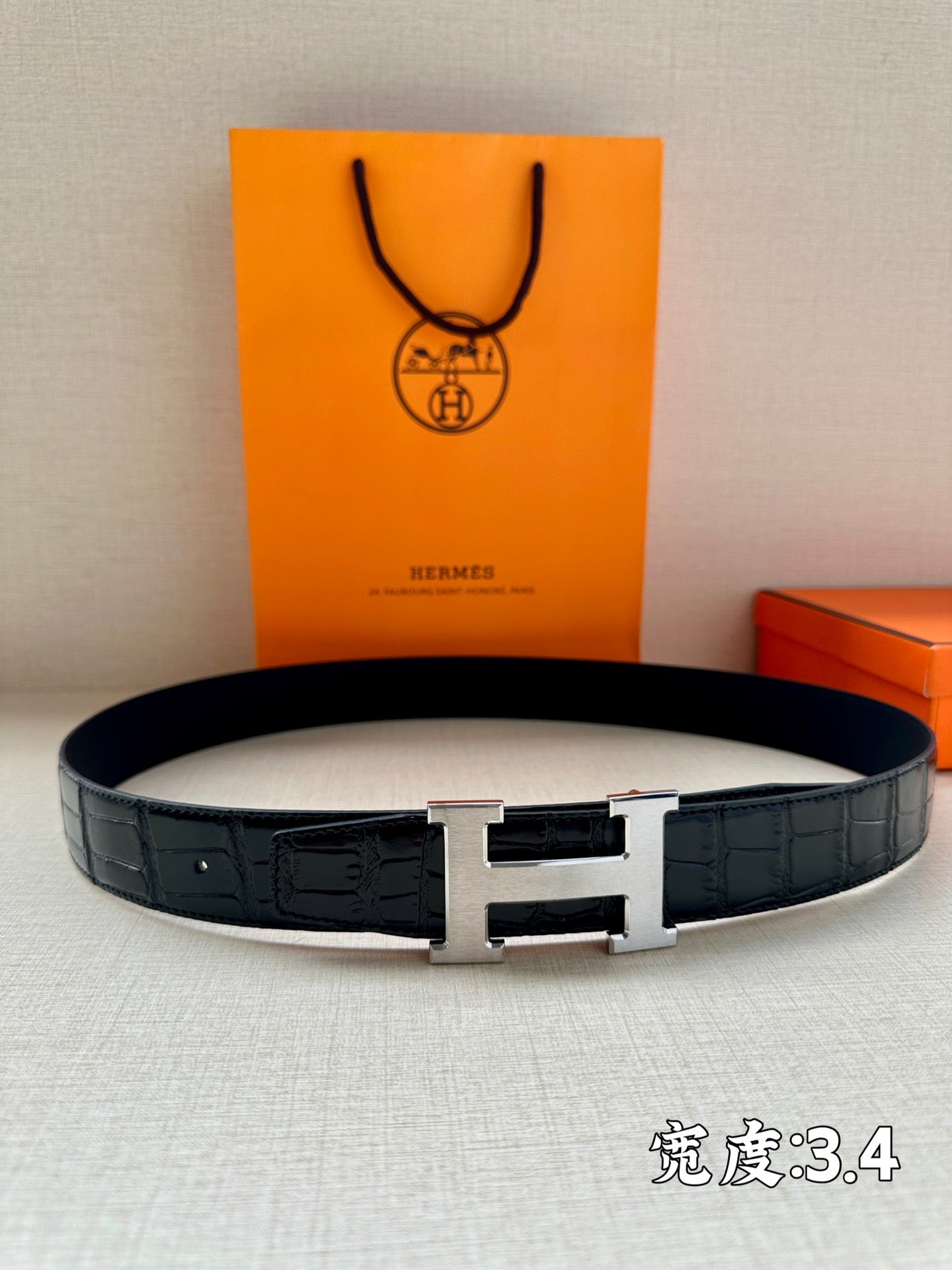 Hermes belt in dark embossed leather with silver H buckle and black strap.