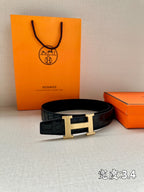Hermes belt with dark embossed leather strap and gold-toned H buckle.