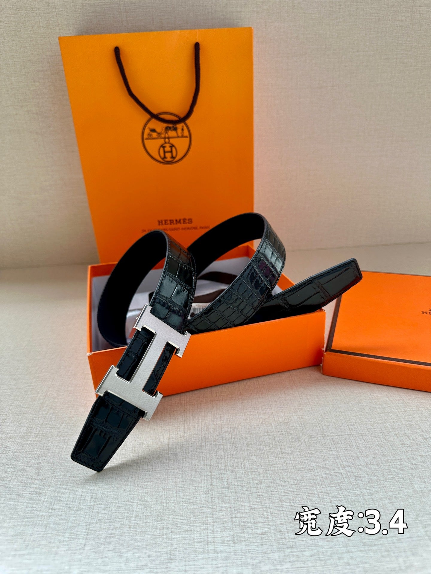 Hermes belt with dark embossed leather strap and large silver H buckle hardware.