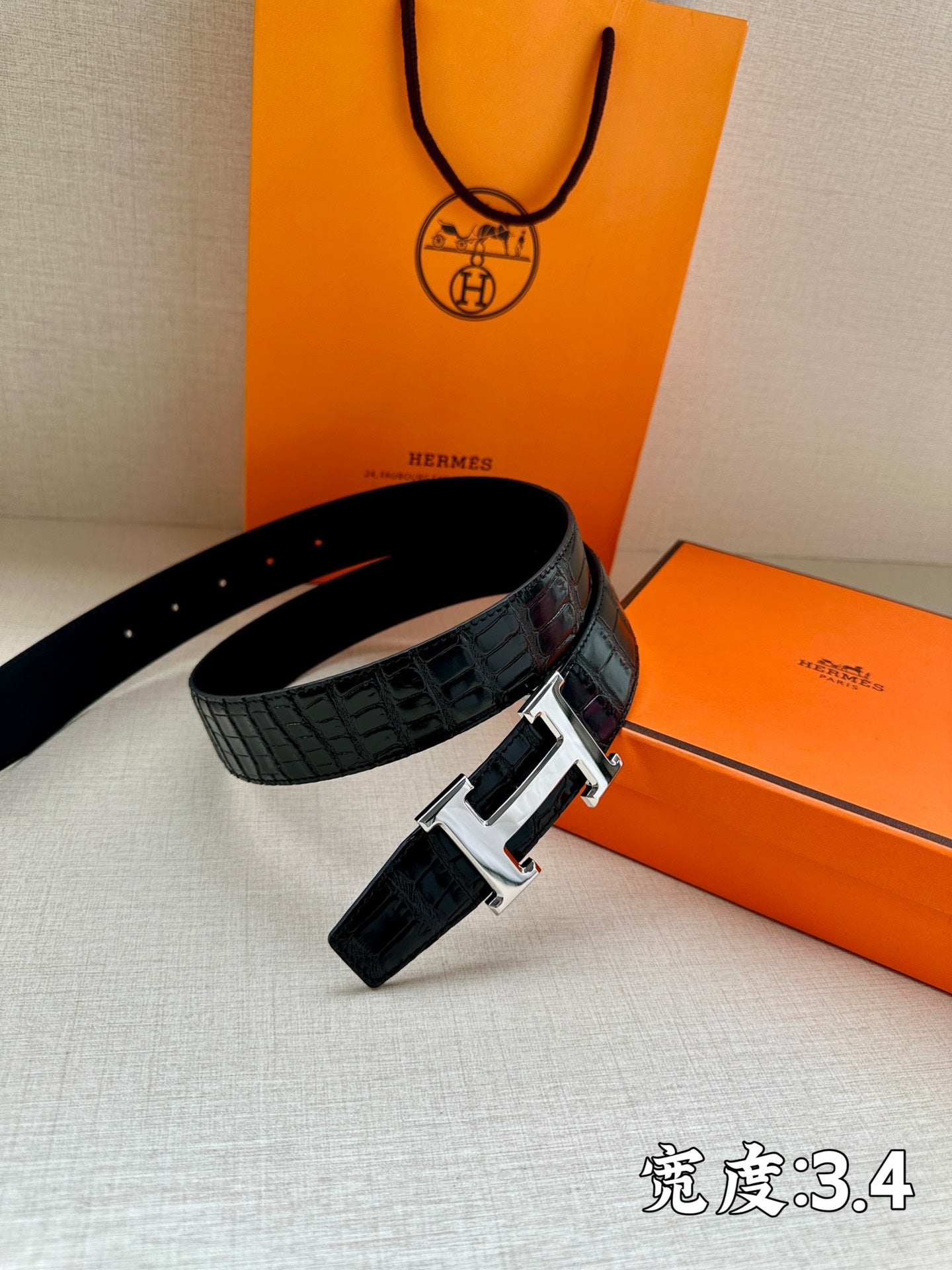Hermes belt with dark embossed leather strap and silver H buckle, angled view