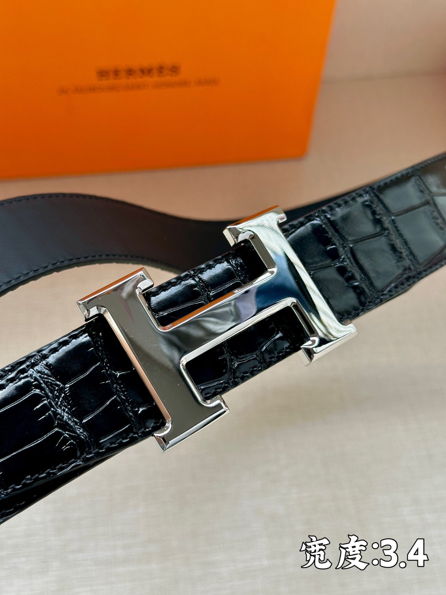 Hermes belt buckle close-up: shiny metal H with dark embossed leather strap