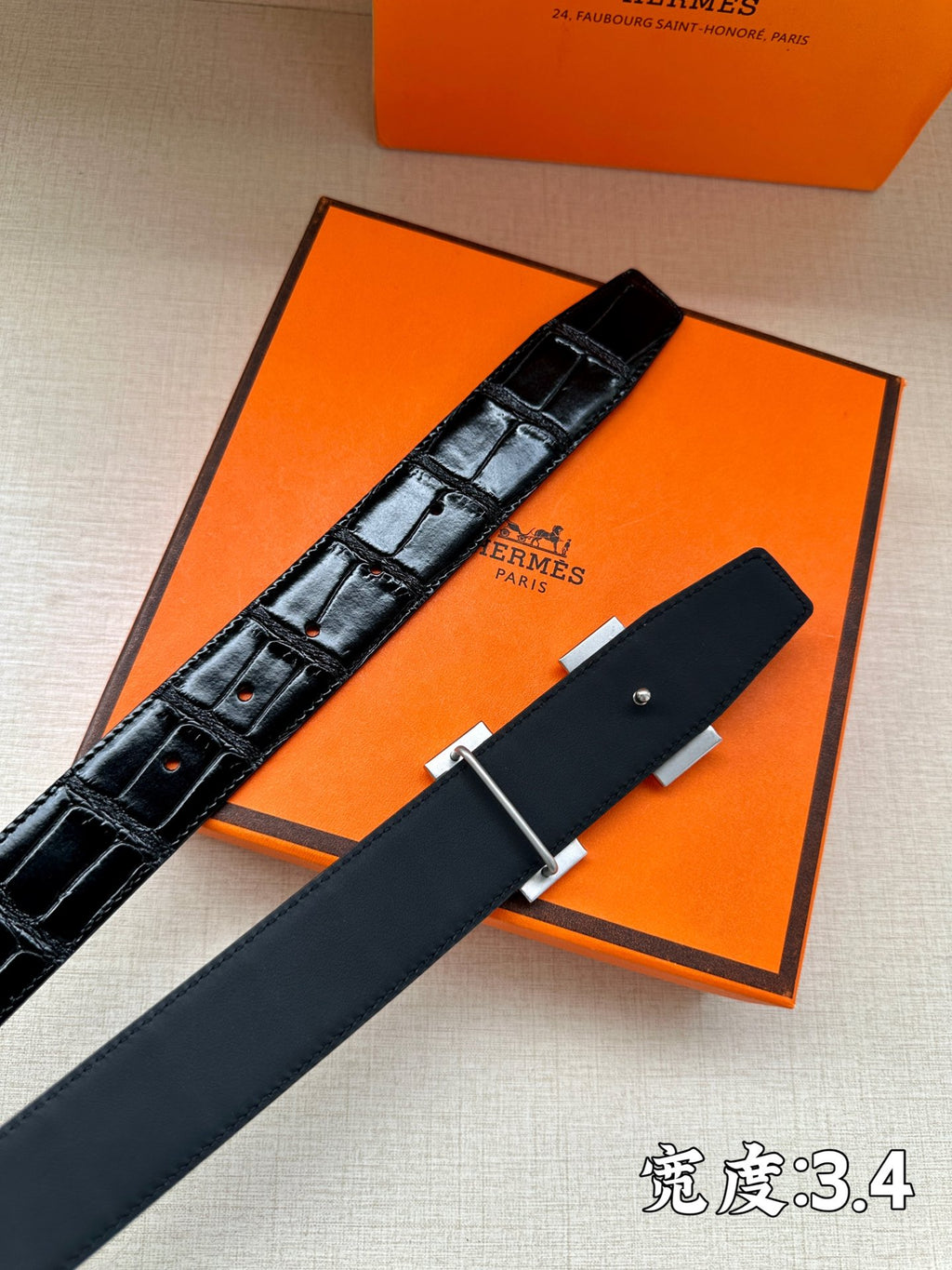 Hermes belt detail with embossed dark leather and silver H buckle on dark strap