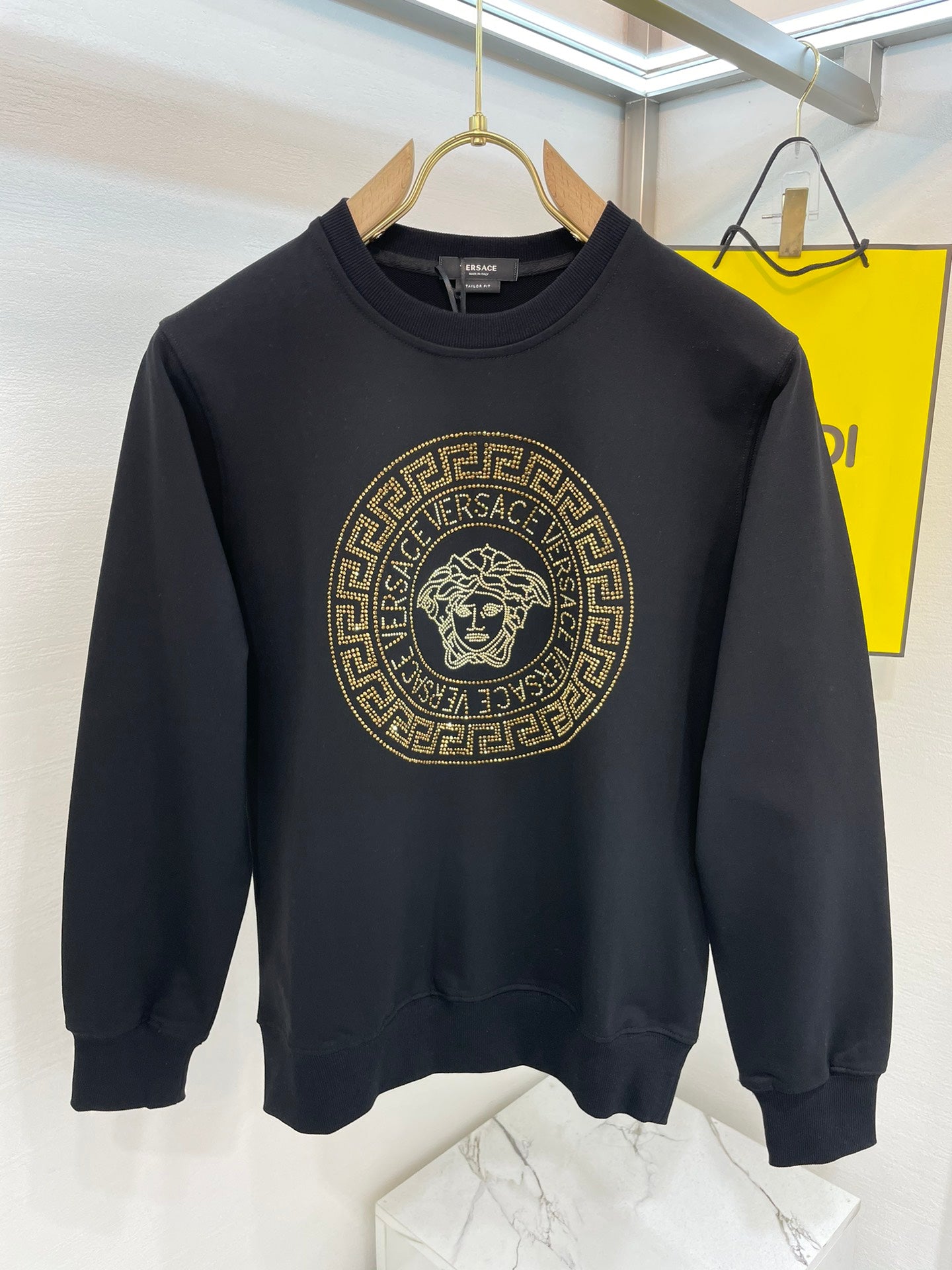 Black crewneck sweatshirt with gold medallion lion logo on front