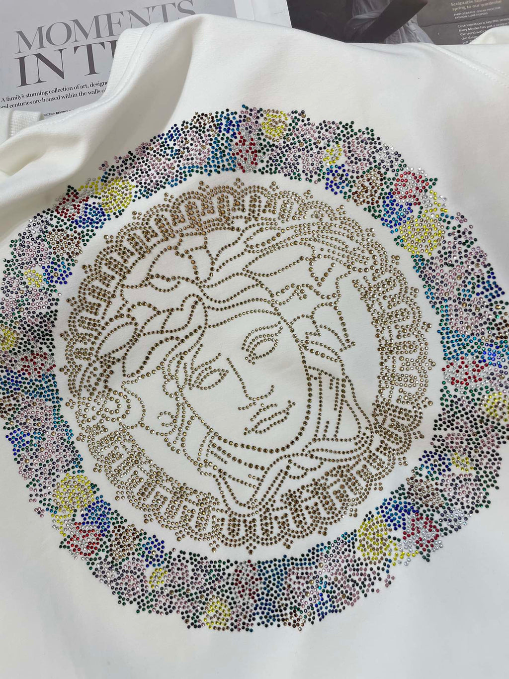 White sweatshirt close-up of multicolor rhinestone Medusa medallion