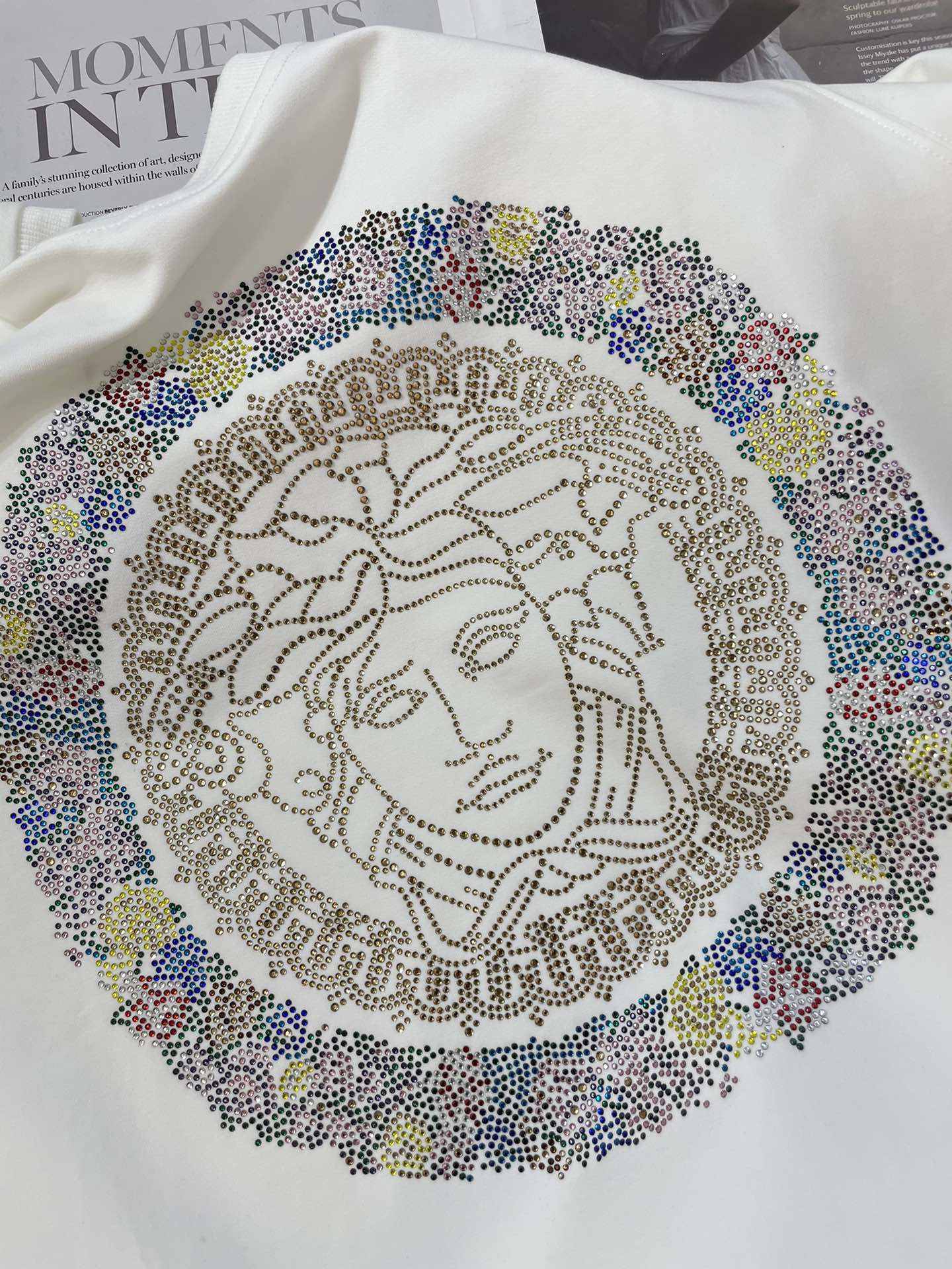 White sweatshirt close-up of multicolor rhinestone Medusa medallion