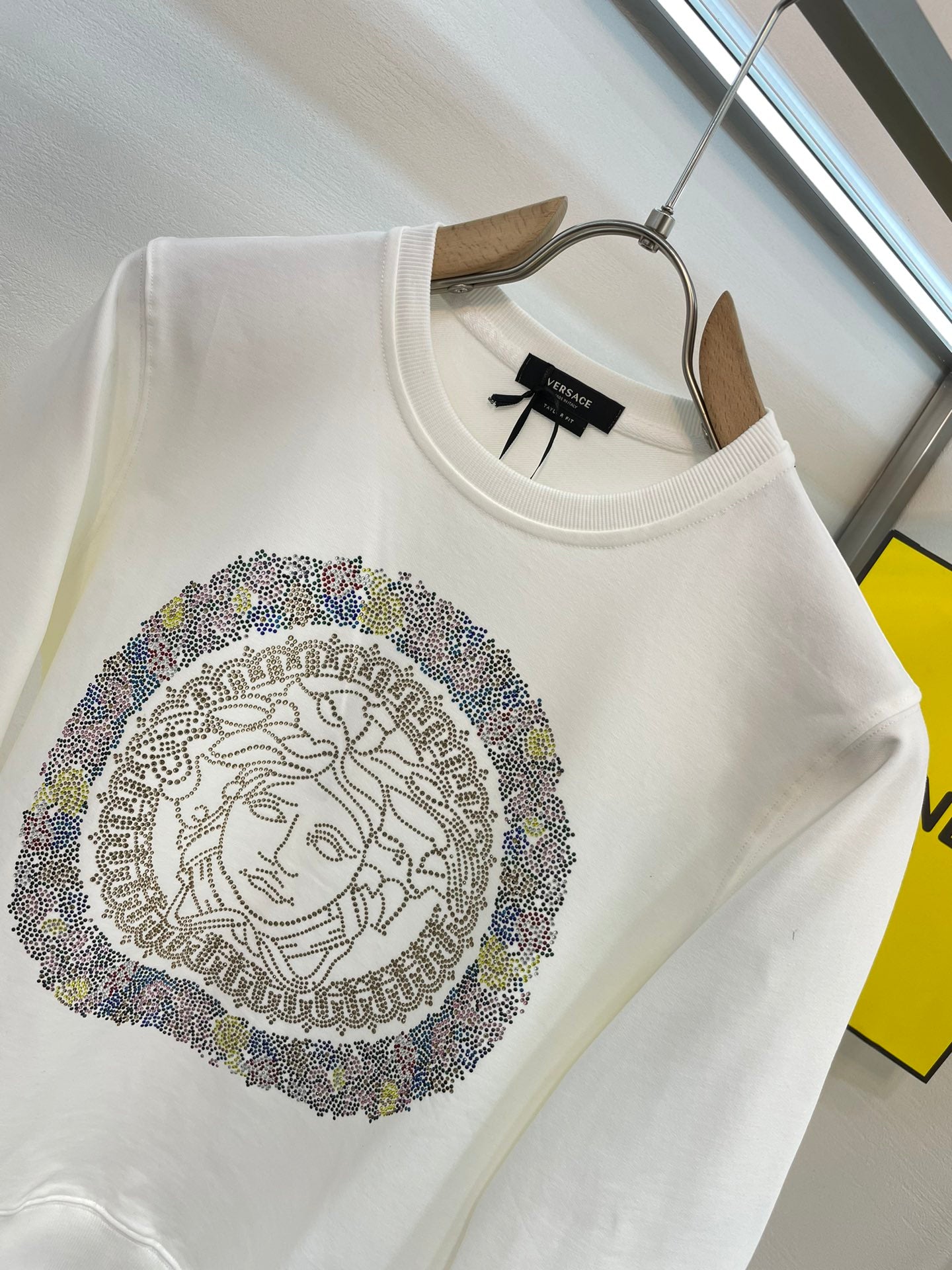 White crewneck sweatshirt featuring rhinestone Medusa medallion artwork