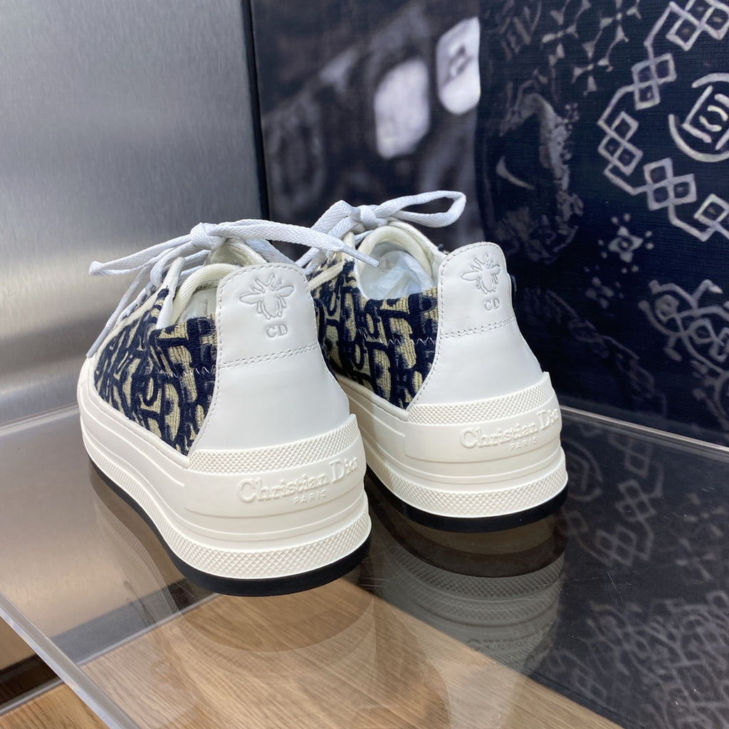 Navy blue logo-print sneakers with white laces; back heel shows Dior branding.