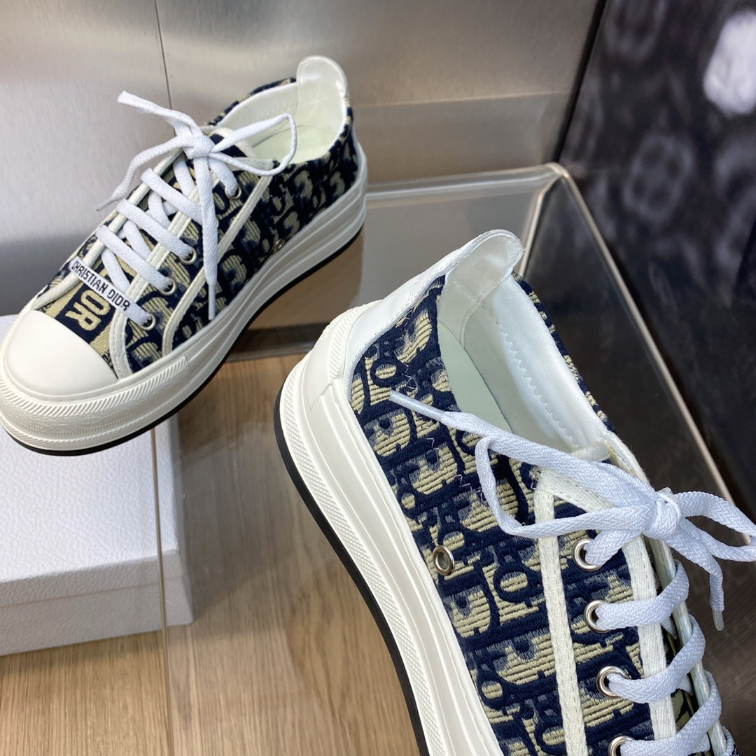 Navy blue logo-print sneakers with white laces, side view with box in frame.