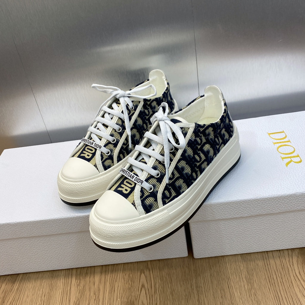 Navy blue and white logo-print low-top sneakers with white laces and thick sole.