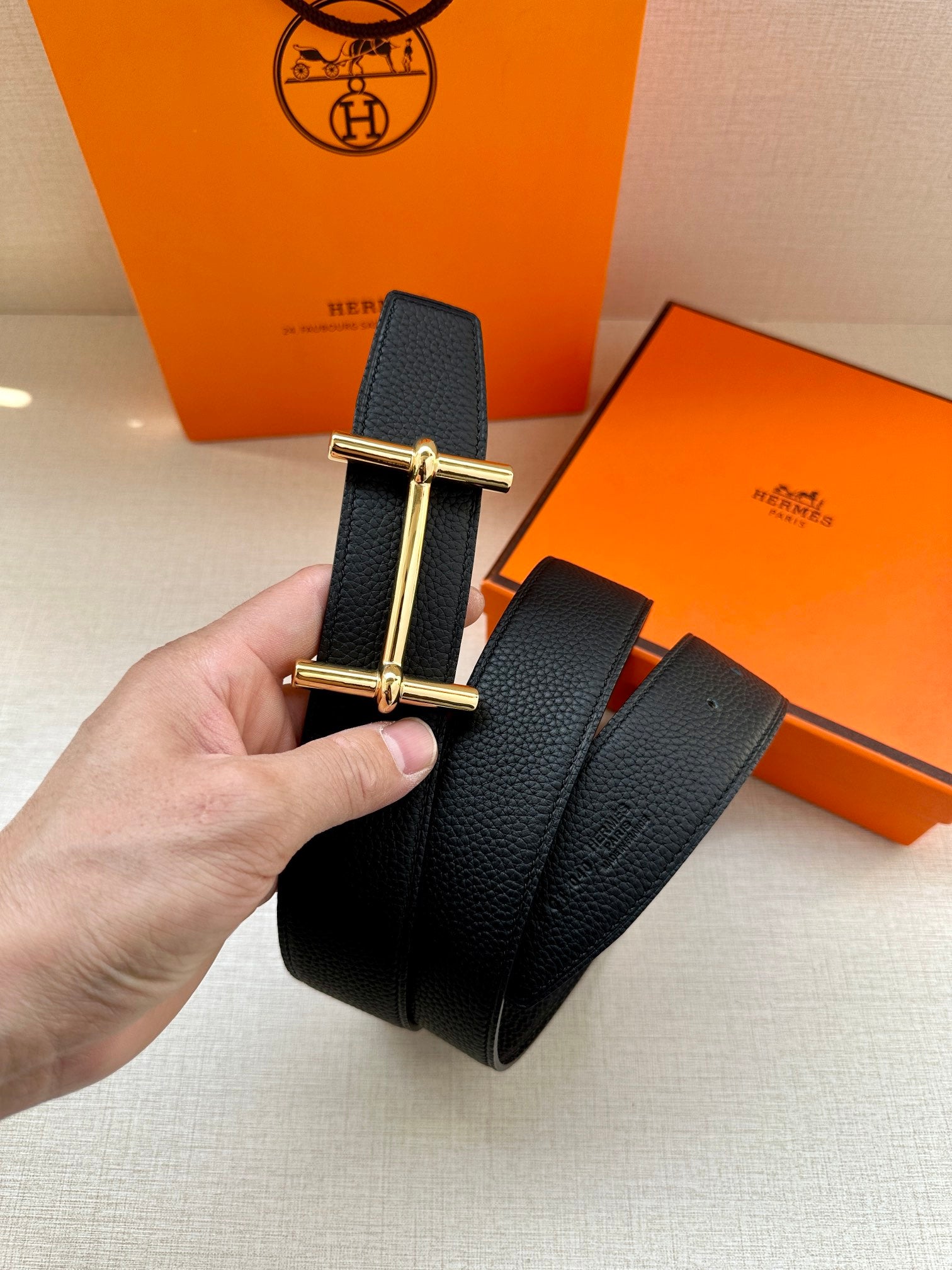 Hermes black leather belt with gold-tone bar buckle, close-up
