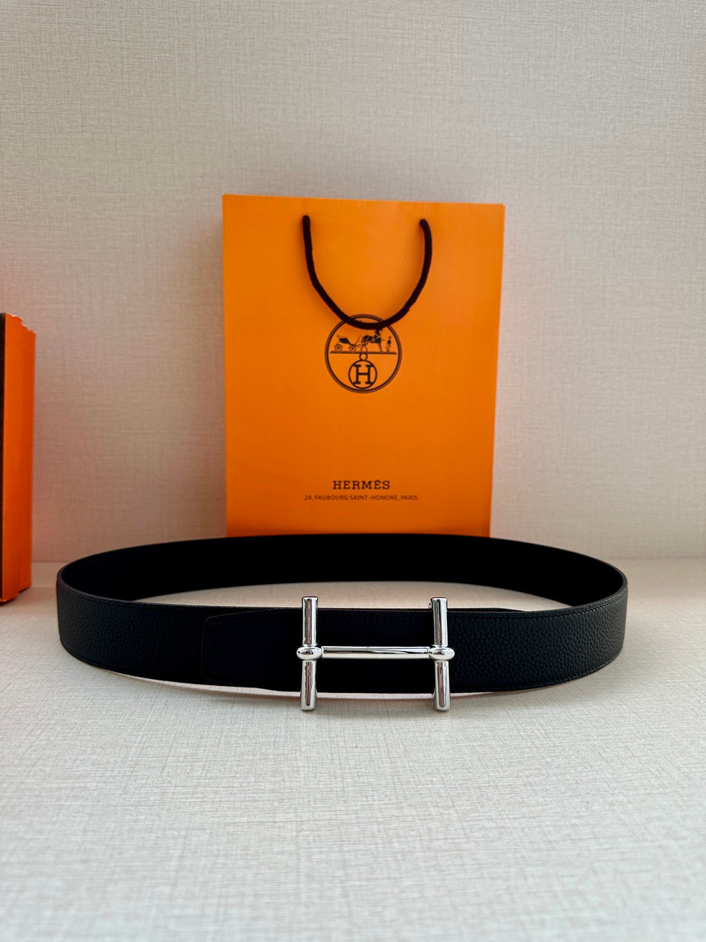 Hermes black leather belt with metal double-prong buckle, flat lay