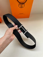 Hermes black leather belt with metal buckle, looped on hand