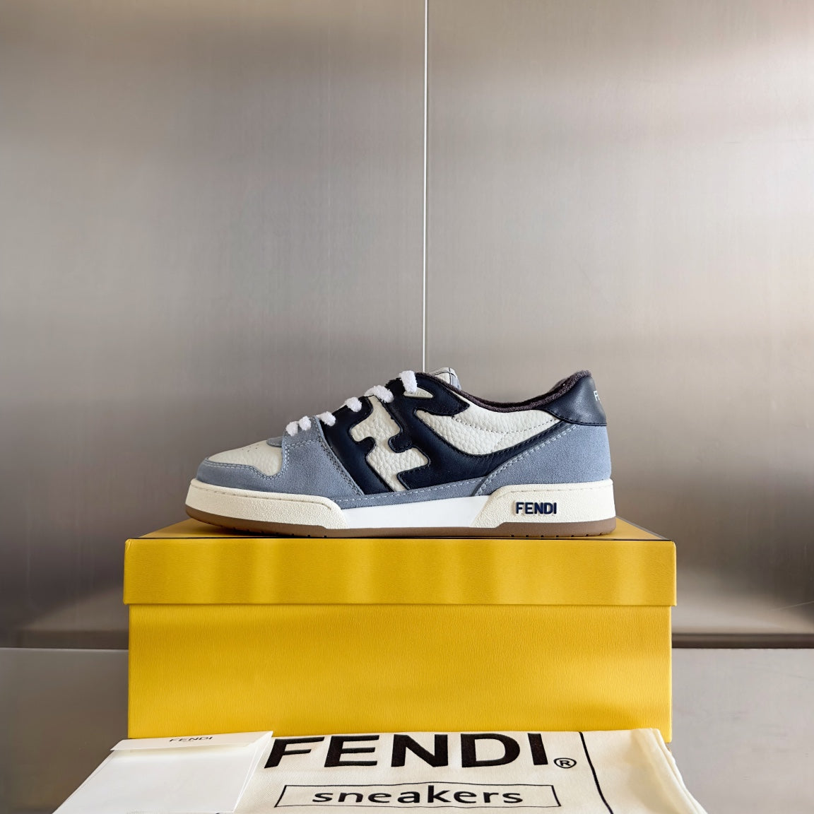 Fendi unisex sneakers on a yellow box, light gray and white with dark navy trim