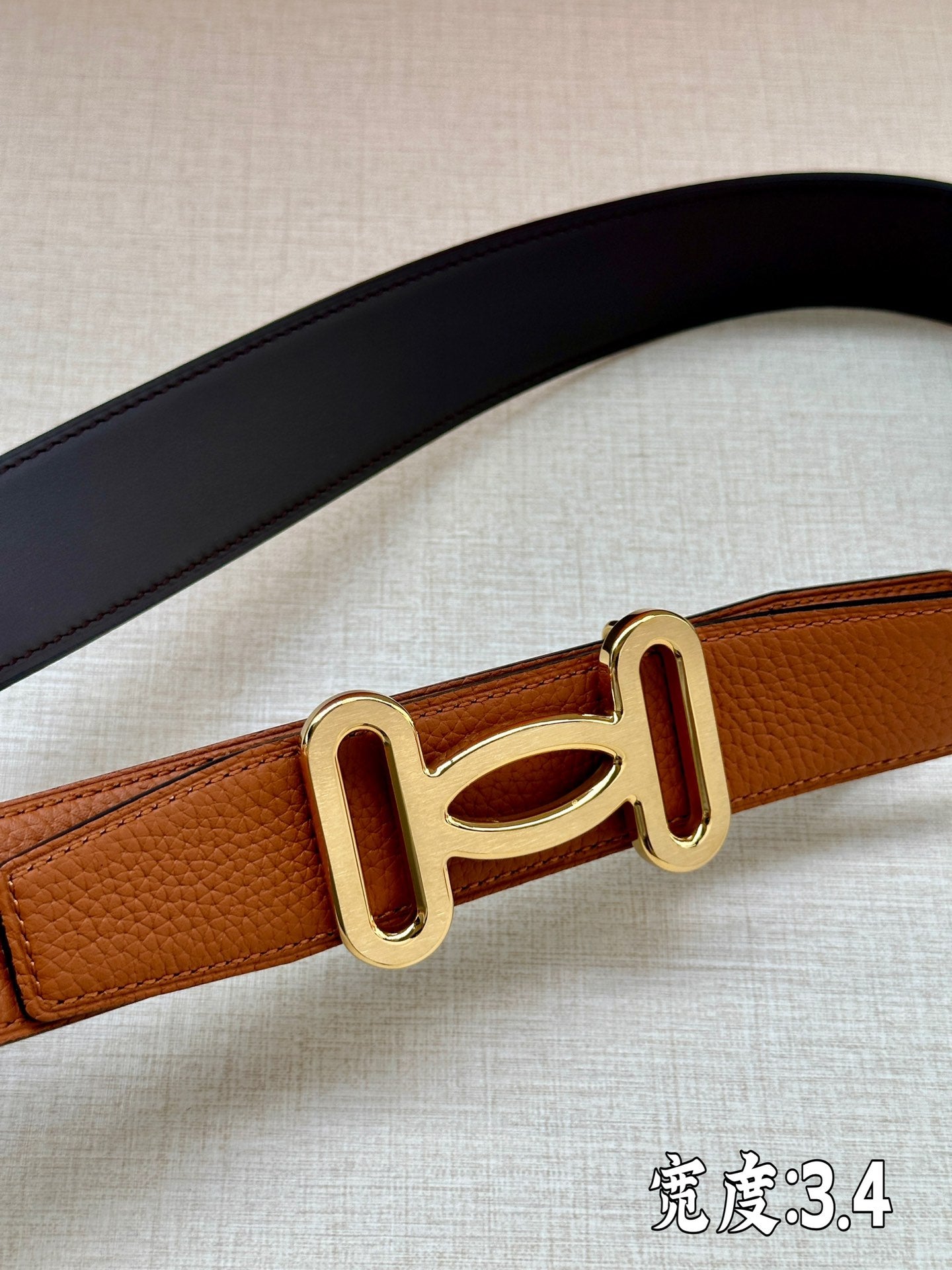 Dark blue and tan leather belts with gold-tone H buckle detail