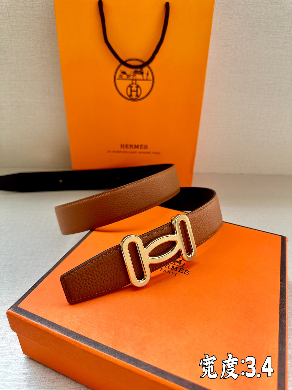 Tan leather belt with gold-tone H buckle, angled view