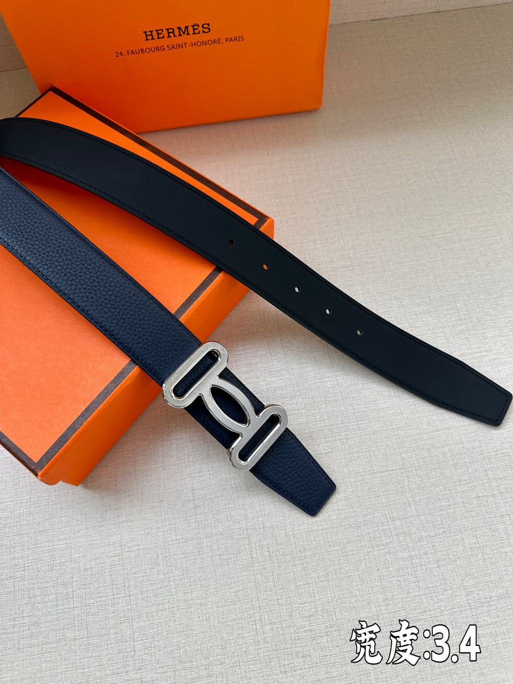 Hermes belt, dark blue leather strap with silver-tone buckle, laid flat.
