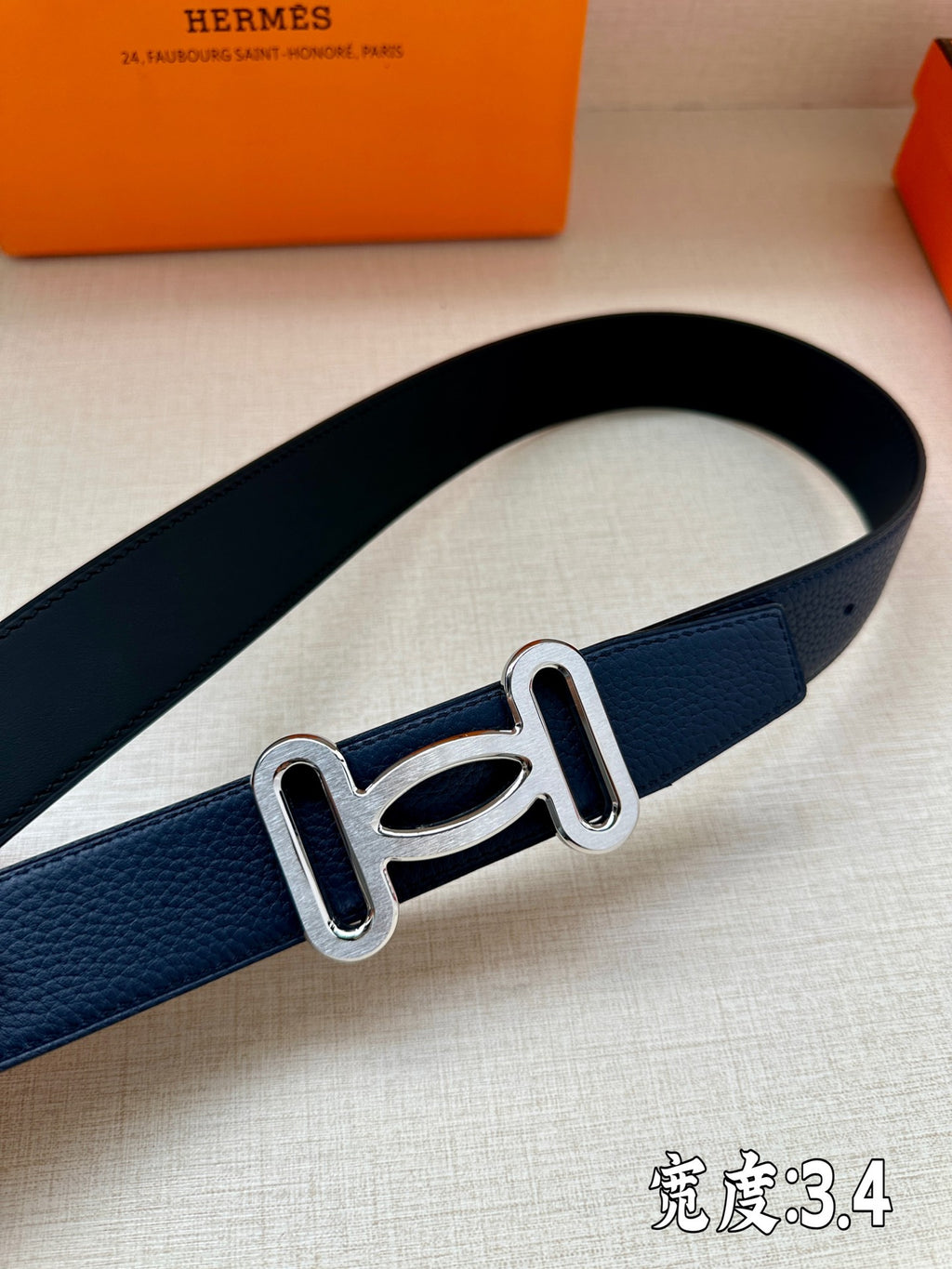 Hermes belt, dark blue textured strap with silver-tone buckle close-up.