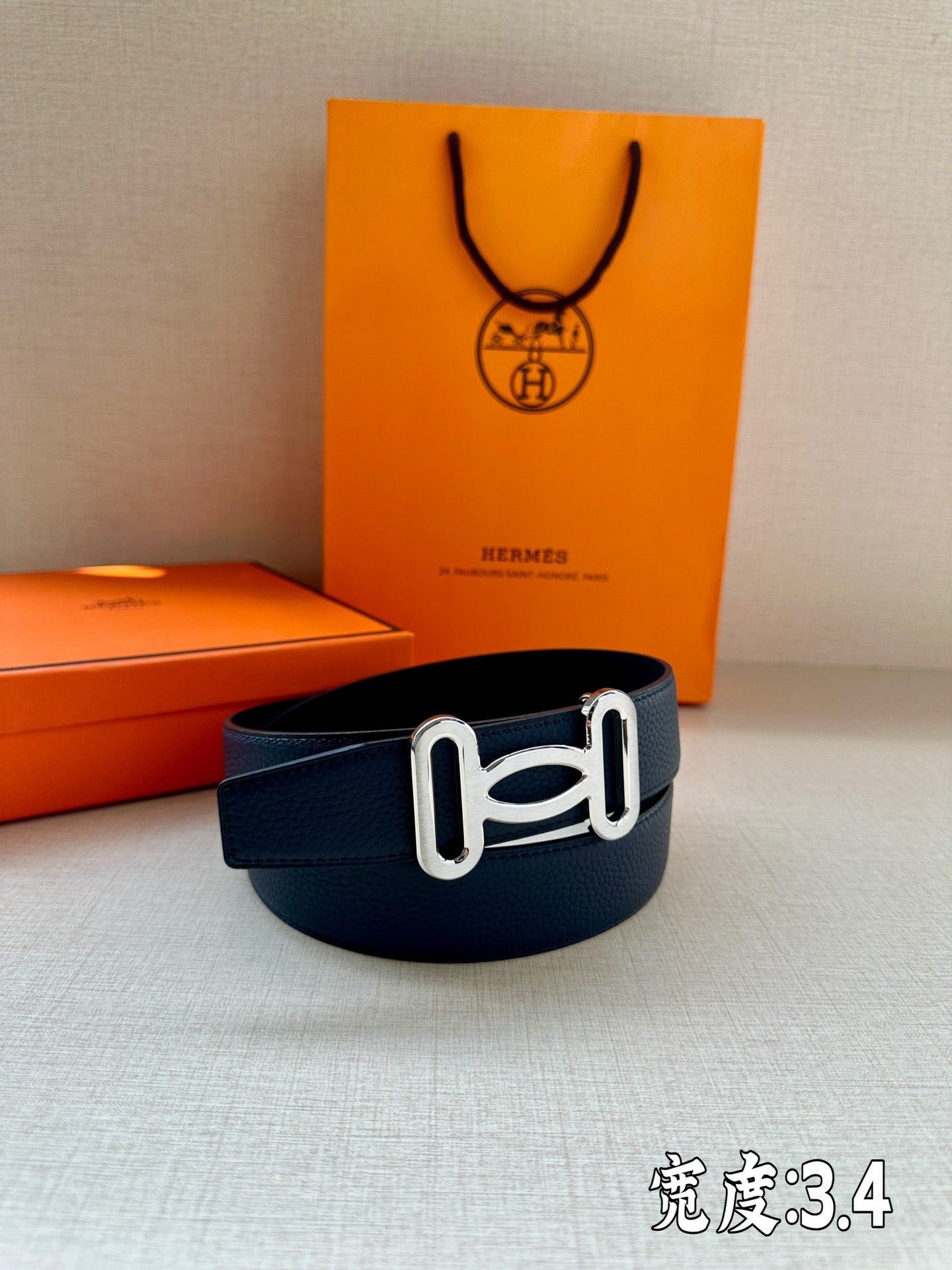 Hermes belt in dark blue leather with silver-tone buckle, front view.