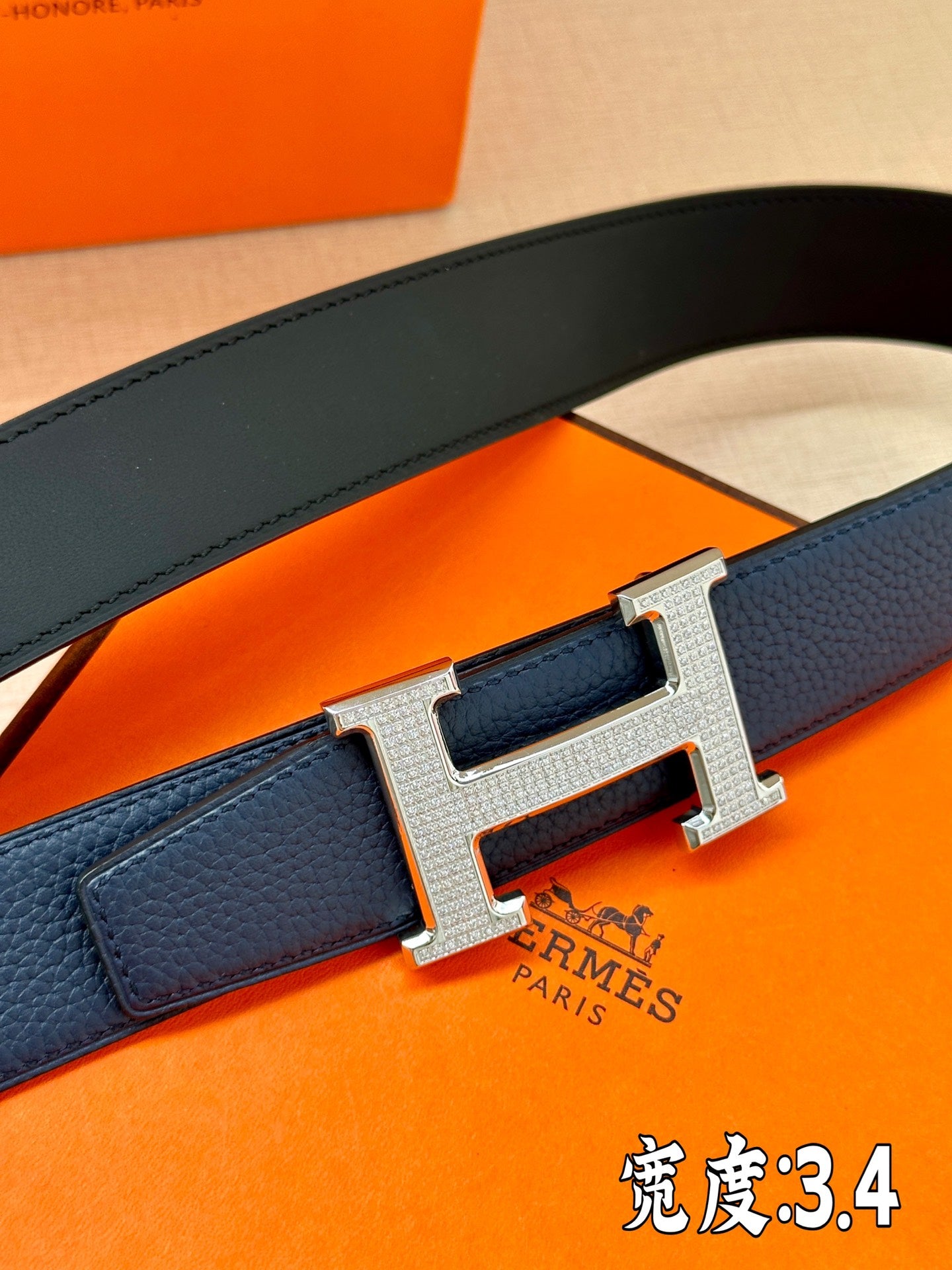 Dark blue leather belt close-up of silver Hermès H buckle and textured strap