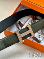 Hermes leather belt close-up in dark green with crystal-like H buckle, rose-gold tone.