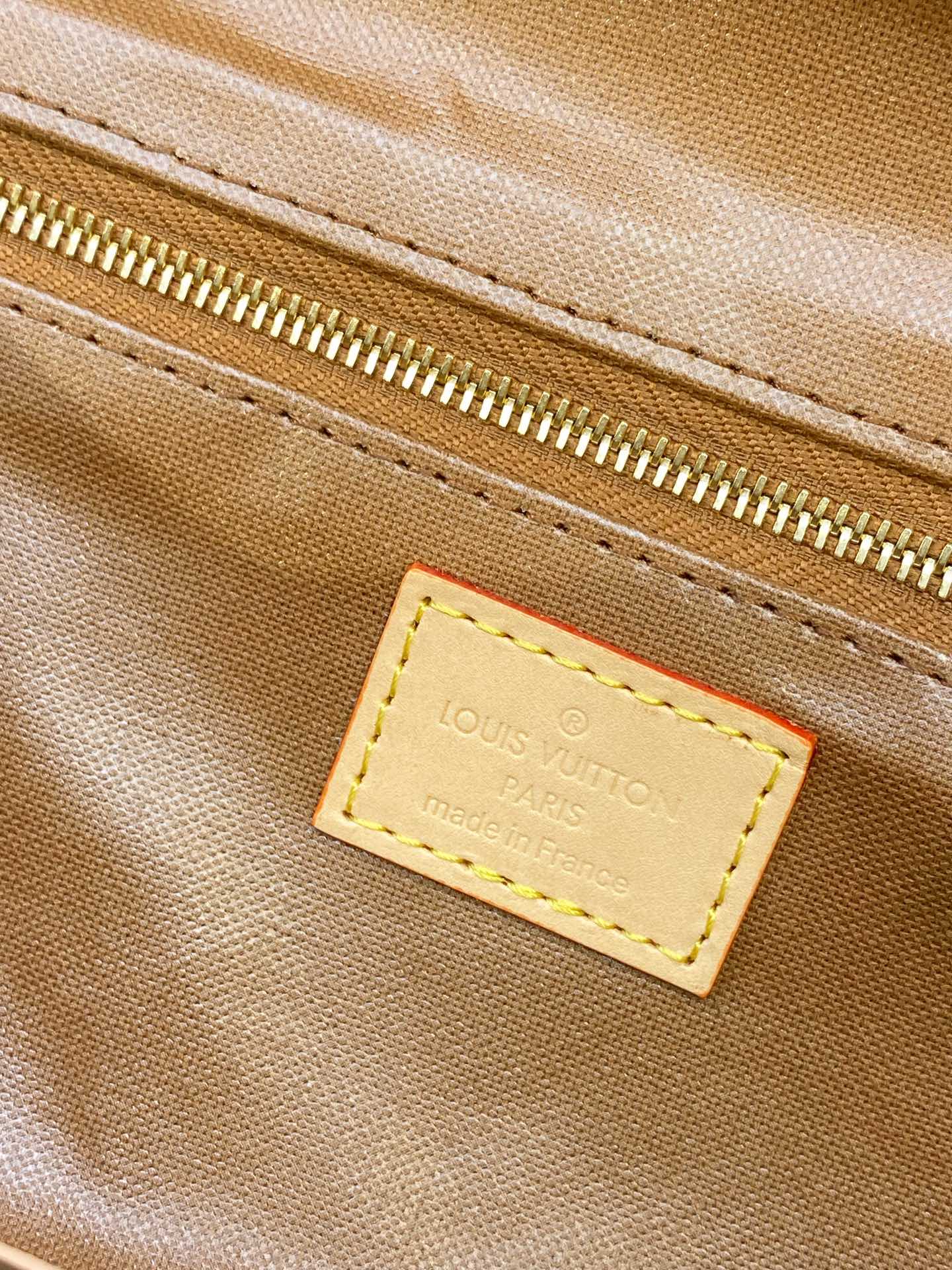 Louis Vuitton leather brand patch on monogram toiletry bag fabric