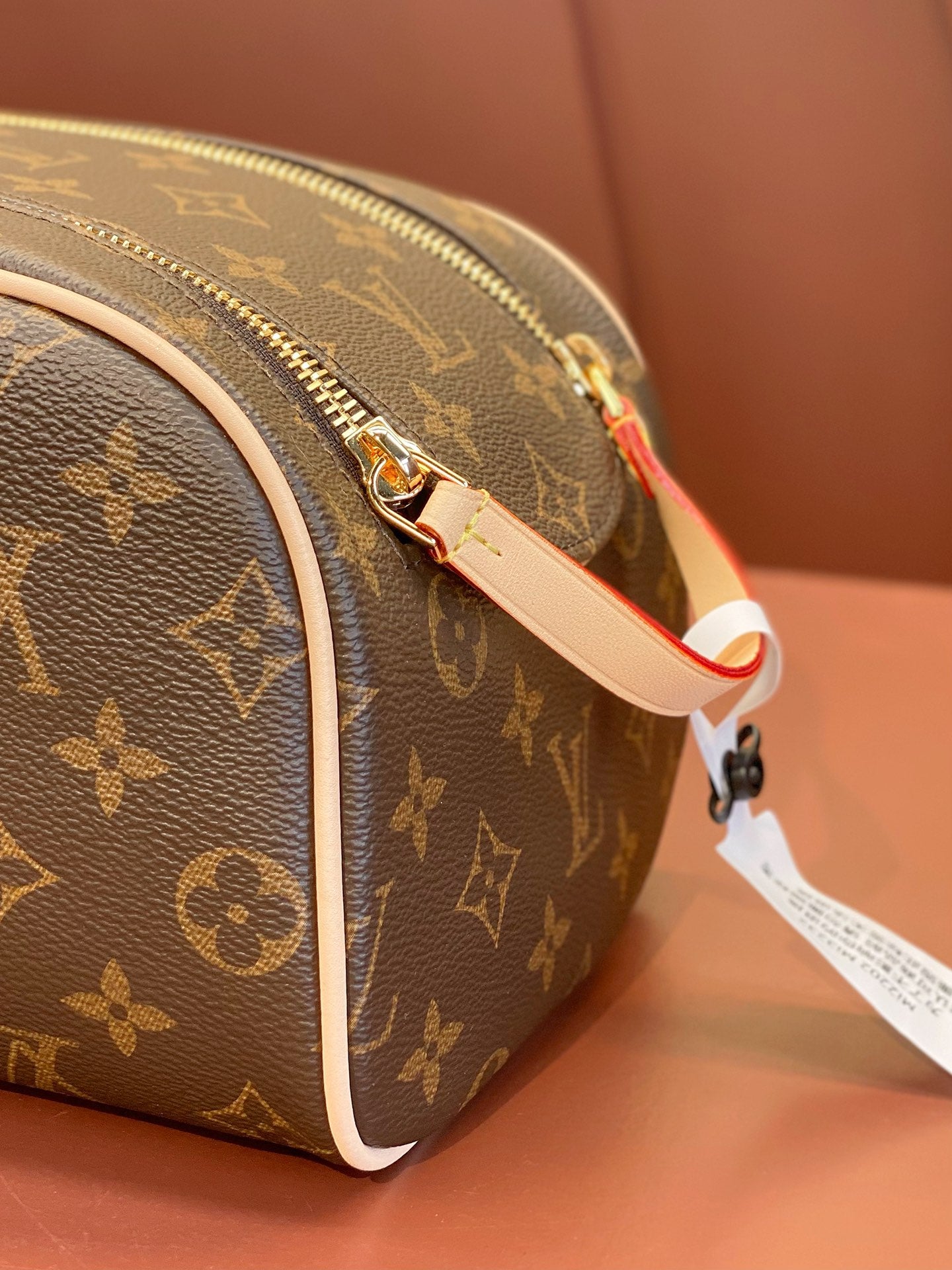 Louis Vuitton monogram toiletry bag with gold hardware, adjustable strap, and tag