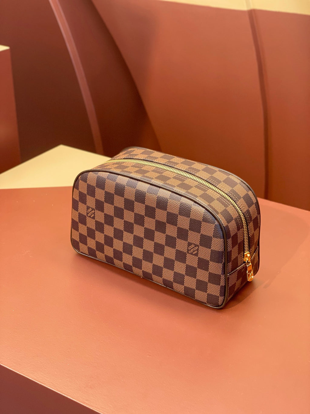 Louis Vuitton checkered toiletry bag with zip-top and brown leather trim.
