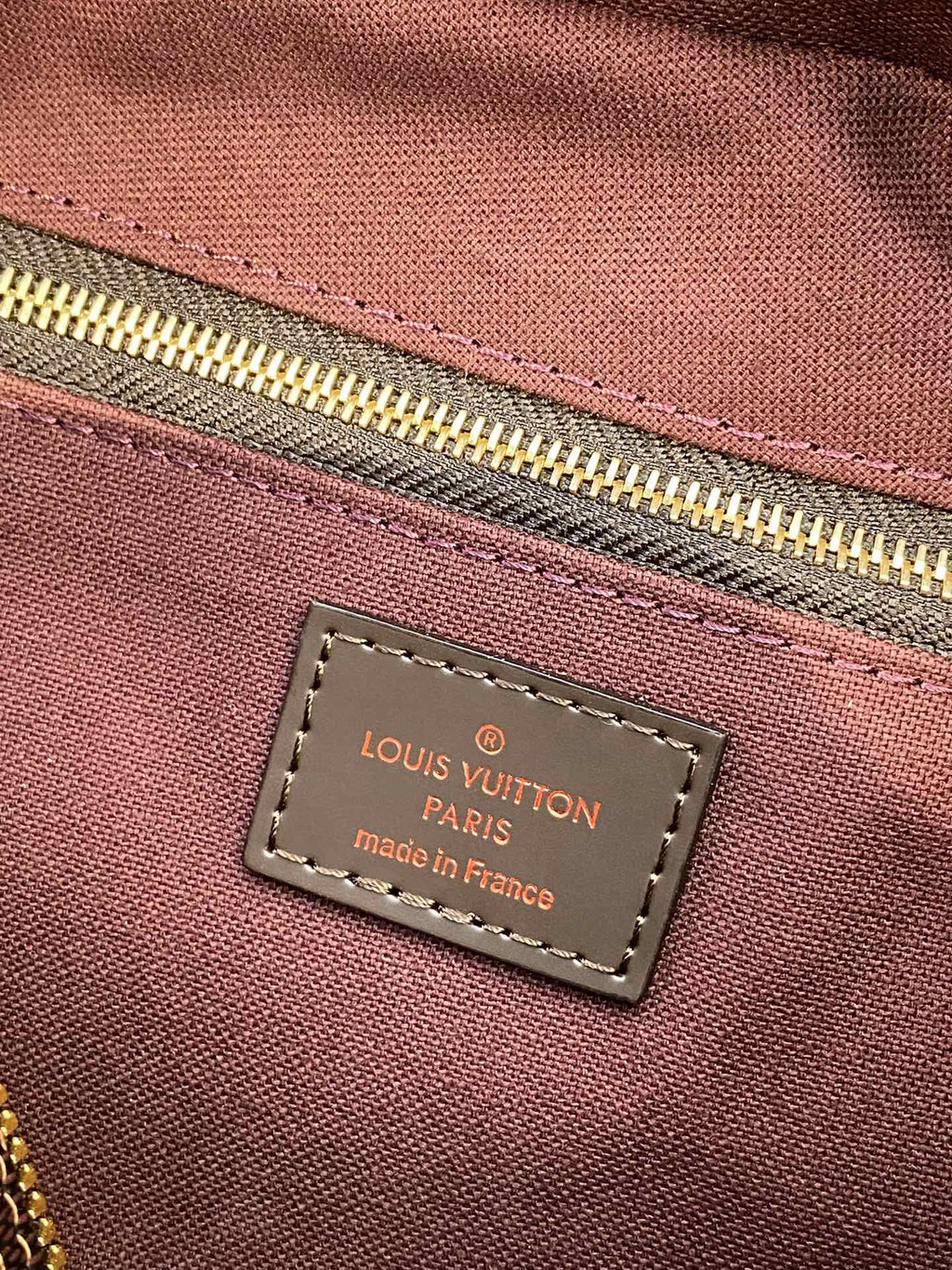 Louis Vuitton Paris made in France label on maroon fabric lining tag.