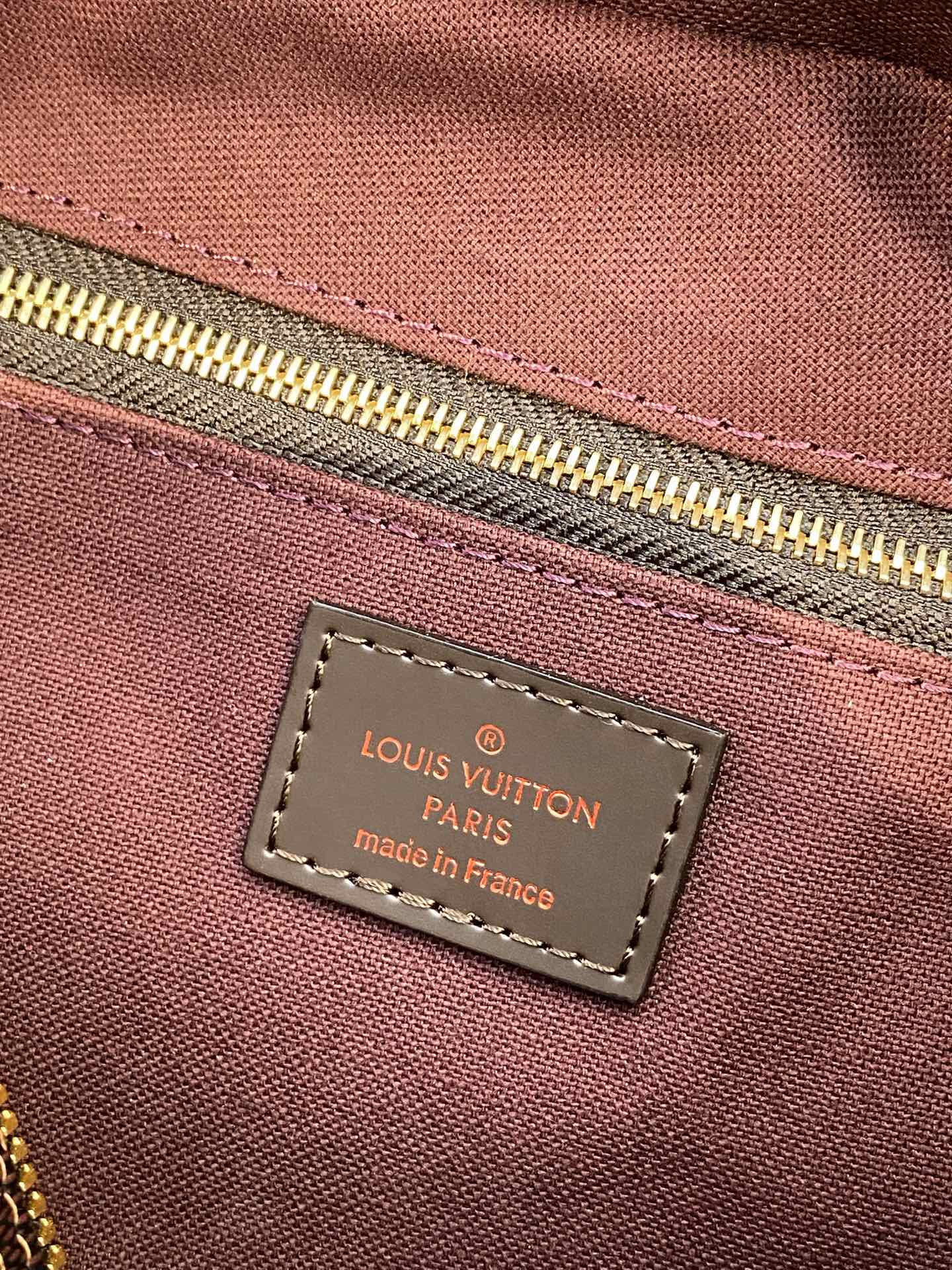 Louis Vuitton Paris made in France label on maroon fabric lining tag.